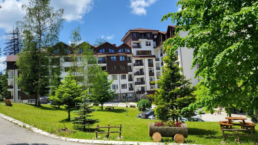 a large apartment building in a park with trees at Alpine luxury two bed-two bathrooms apartment B25 in Borovets