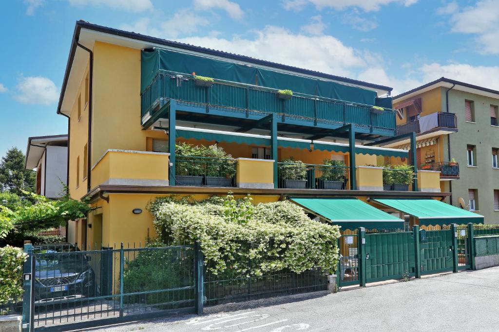 un edificio con una recinzione verde di fronte ad esso di 3V apartments Bardolino a Bardolino