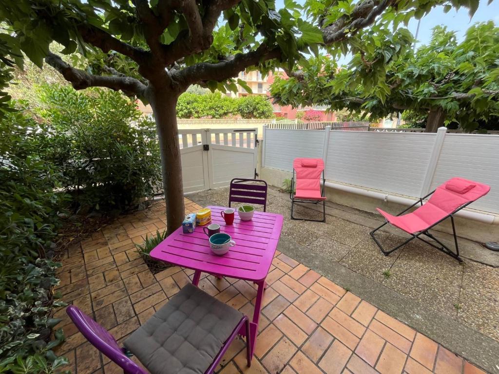 une table et des chaises roses sous un arbre sur une terrasse dans l'établissement Appartement en rez-de-chaussée avec terrasse à Narbonne Plage 4MED301, à Narbonne-Plage
