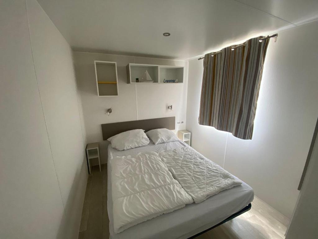 niewielka sypialnia z łóżkiem i oknem w obiekcie Mobilheim Wattwurm mit Veranda am Kransburger See 555 w mieście Kransburg