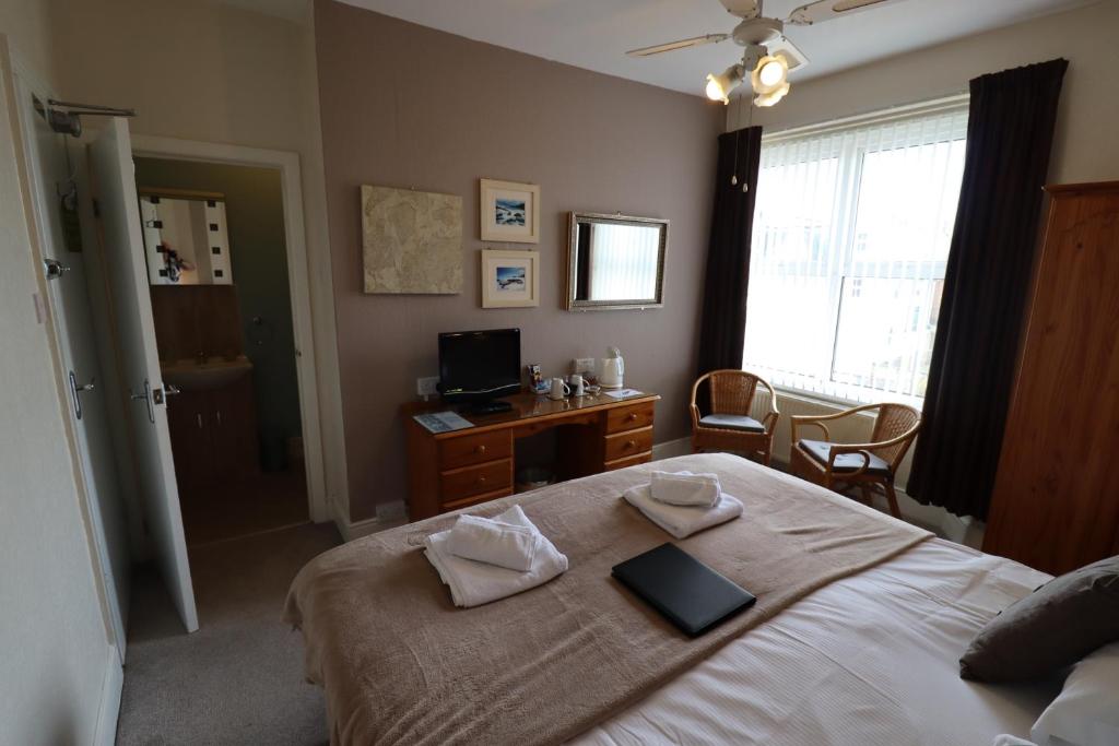 a bedroom with a bed and a desk with a computer at Merritt Guest House B&B in Paignton