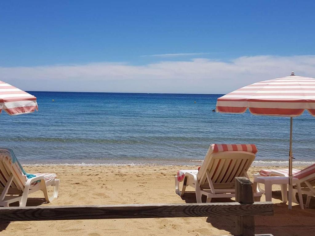 zwei Stühle und ein Sonnenschirm am Strand in der Unterkunft T3 climatisé avec jardin à 200 m de la plage - FR-1-100-249 in Cavalaire-sur-Mer