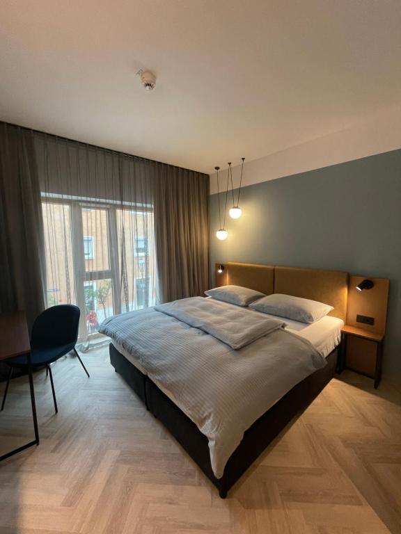 a bedroom with a large bed and a chair at Stadthotel Neumarkt Mitte in Neumarkt in der Oberpfalz