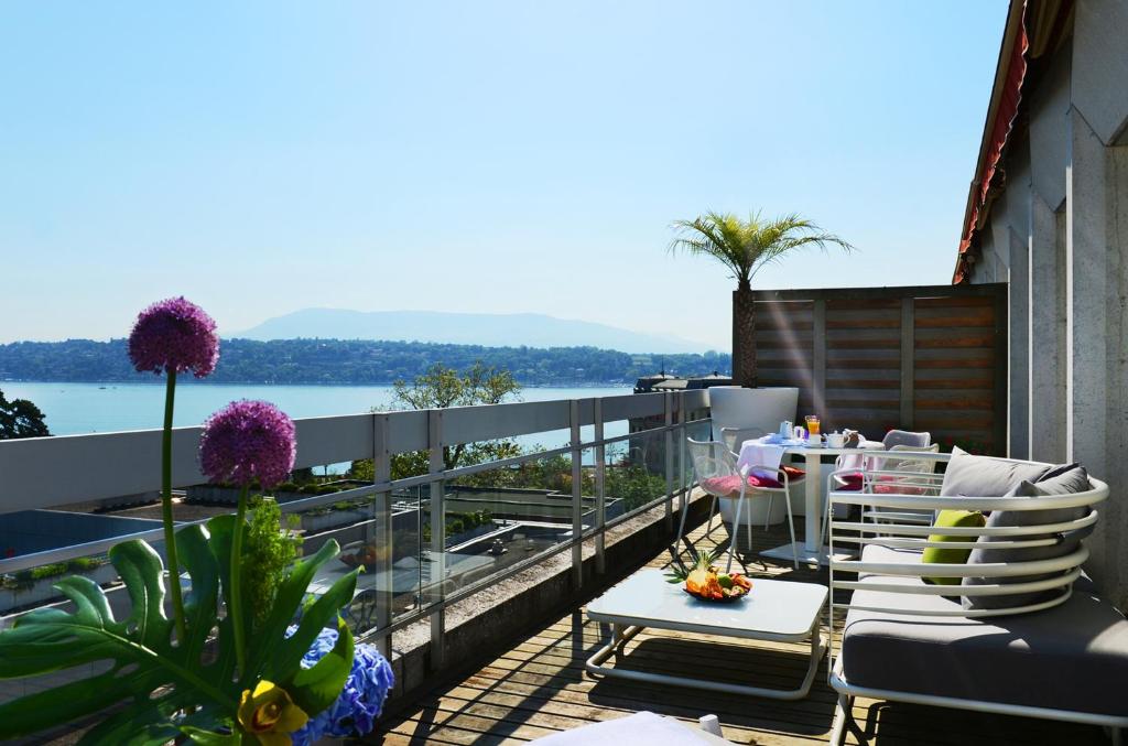 a balcony with chairs and a table and a view of the water at N’vY Manotel in Geneva