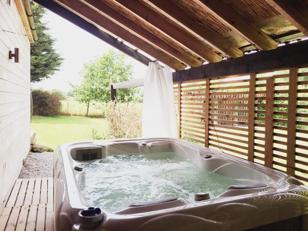 een hot tub in de achtertuin met een raam bij Out & LODGE Les Spirous in Les Géronsarts