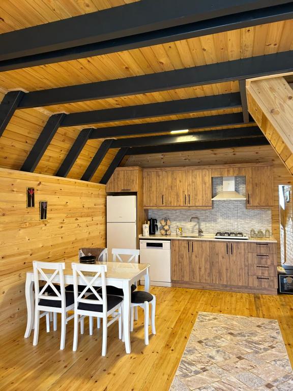 uma cozinha com paredes de madeira e uma mesa e cadeiras em Azhara Bungalov em Pelitli