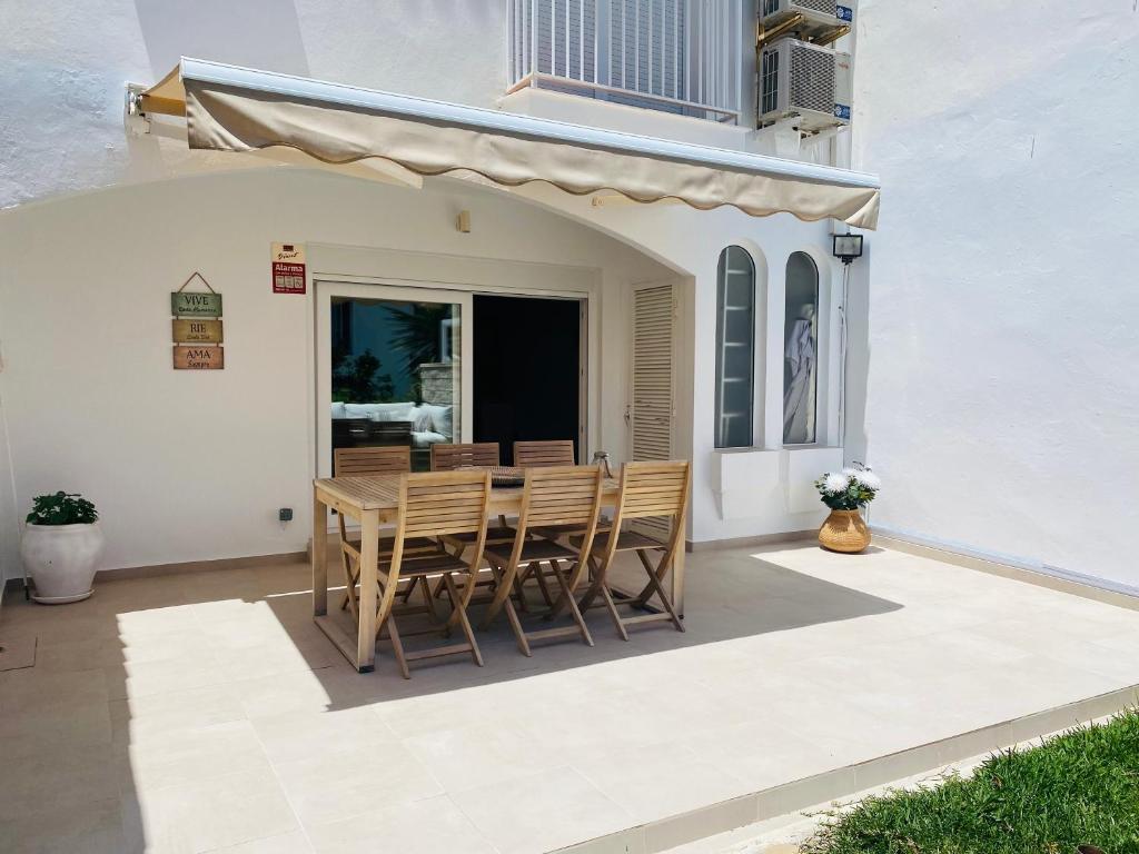 een patio met een tafel en stoelen voor een gebouw bij Happy Beach House in Manilva