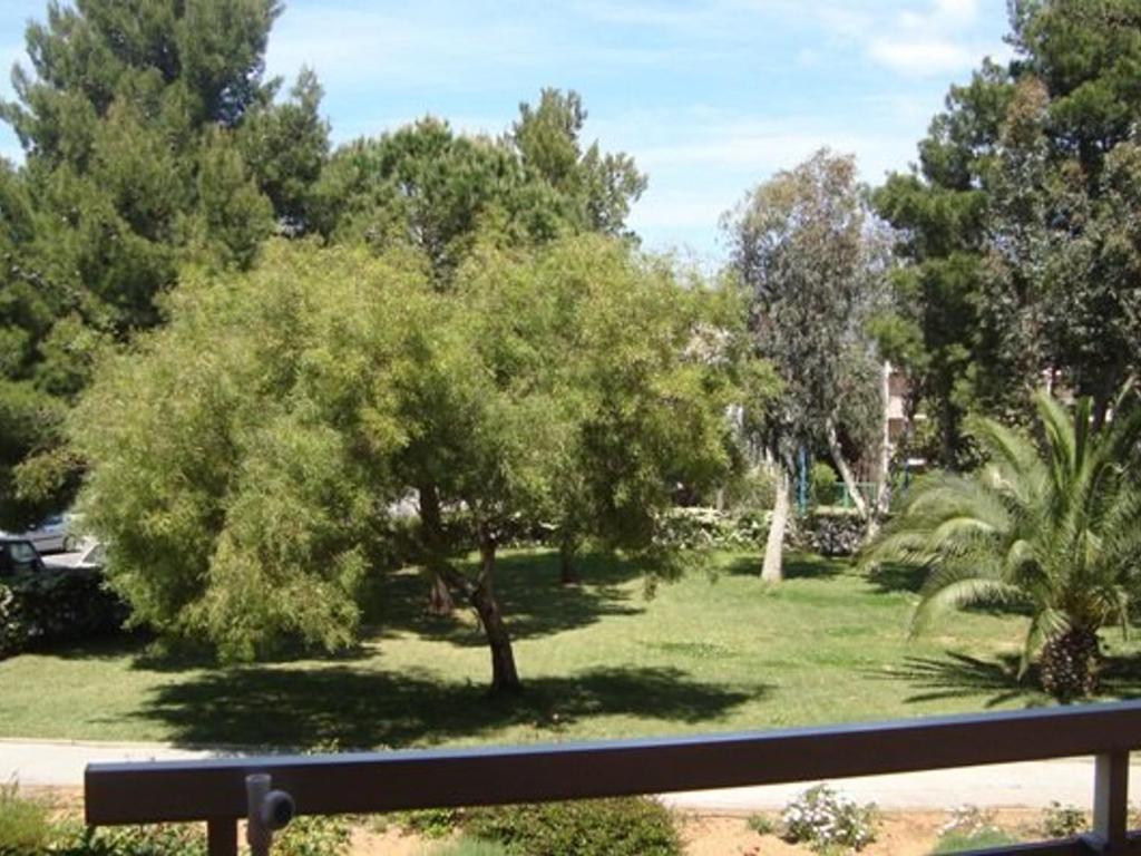 un parc avec un banc et un arbre dans l'établissement T2 cabine proche plages et commerces avec garage à Bormes-les-Mimosas - FR-1-610-60, à Bormes-les-Mimosas