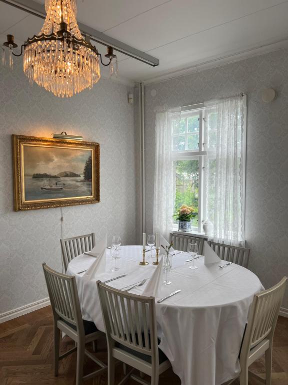 a dining room with a white table with chairs and a chandelier at Göta Hotell in Borensberg