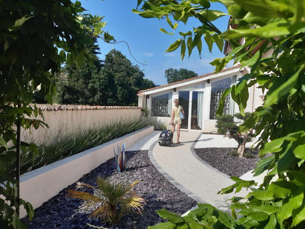 a woman standing on a walkway in a garden at Un petit coin de paradis à Haute Jarrie in Jarrie