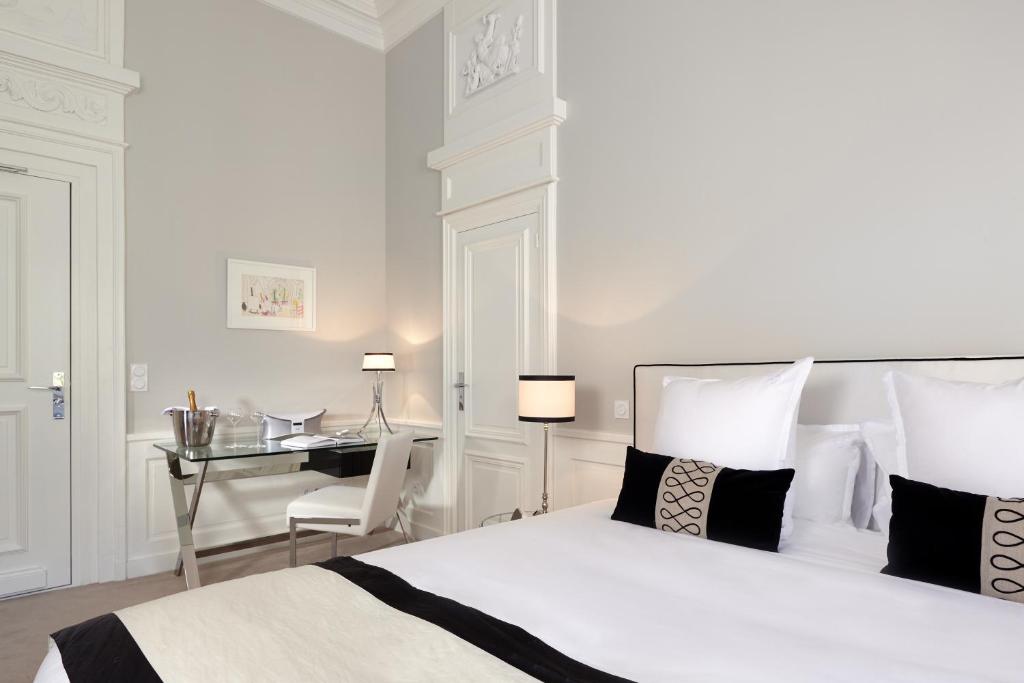 a white bedroom with a bed and a desk at Clarance Hotel Lille in Lille
