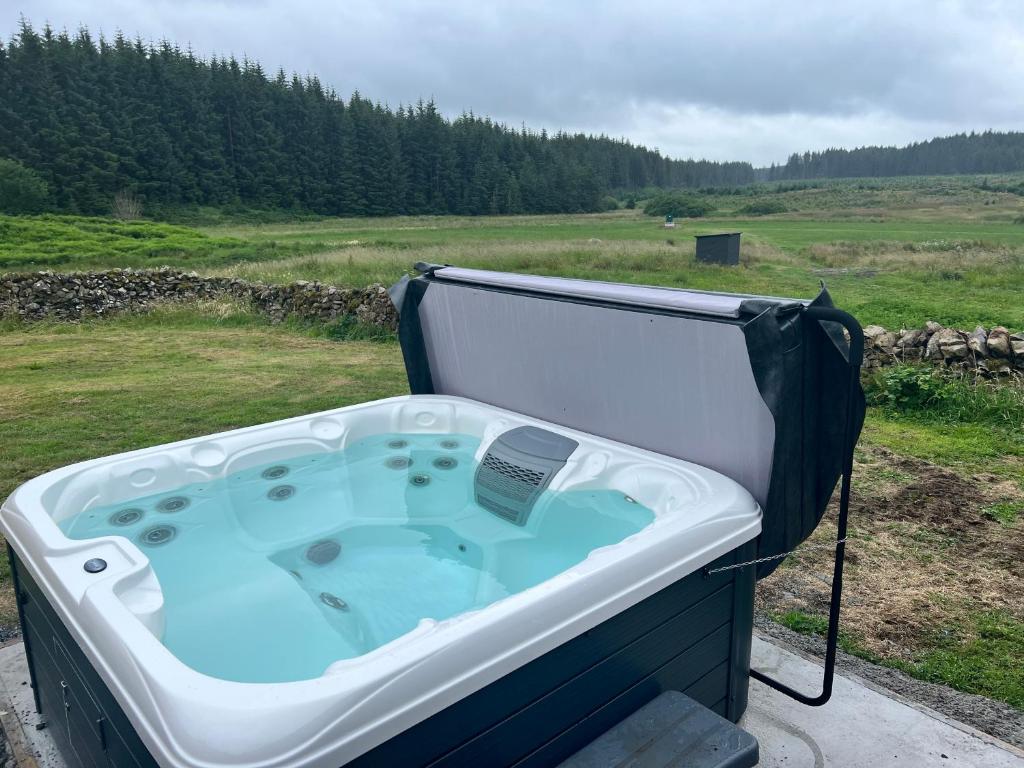 a hot tub sitting on top of a field at Merrick Cottage in Bargrennan