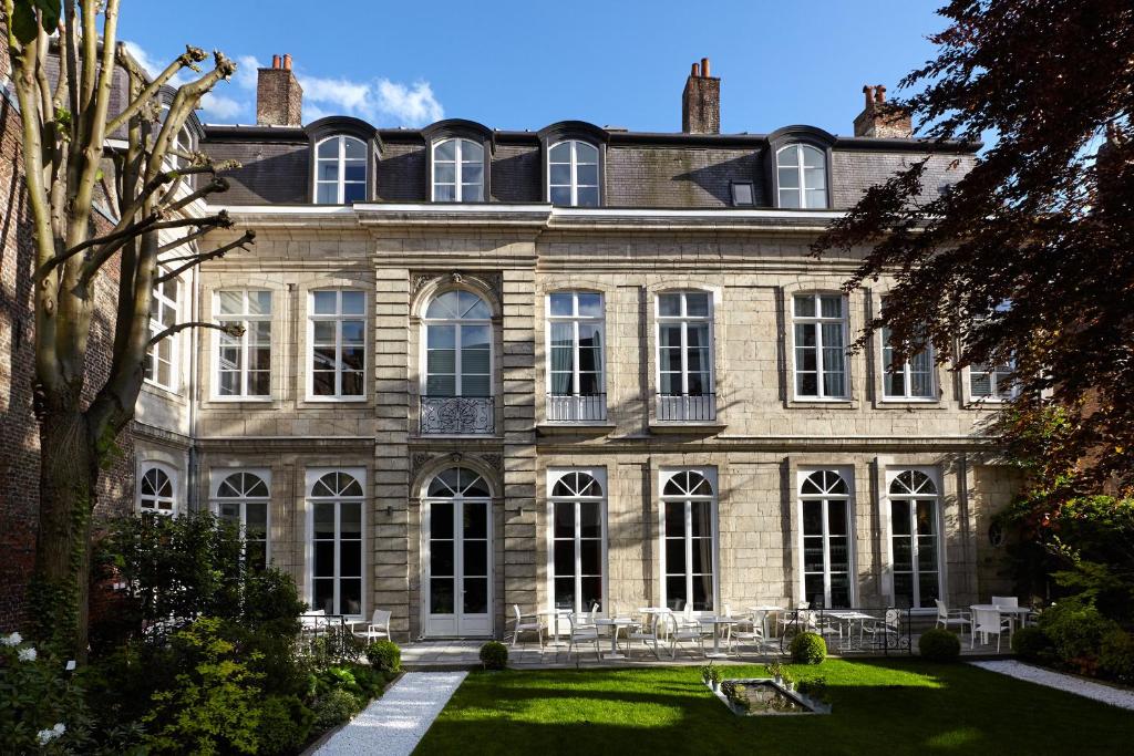 an old stone house with a lawn in front of it at Clarance Hotel Lille in Lille