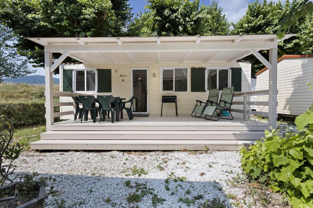 Cottage mit einem Tisch und Stühlen auf einer Veranda in der Unterkunft Bungalow Maple 8 in Ameglia