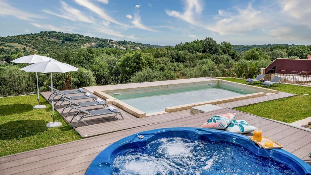 a large swimming pool with a deck and an umbrella at VILLA SUMAC 6, Emma Villas in Sortino