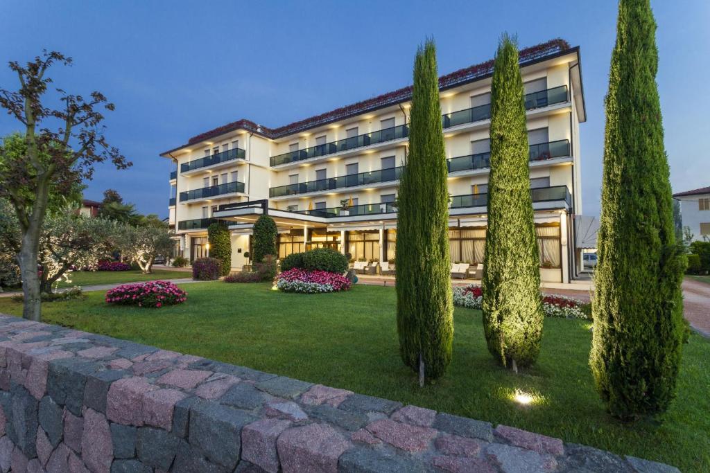アーバノ・テルメにあるAtlantic Terme Natural Spa & Hotelの建物の前に木々が茂るホテル