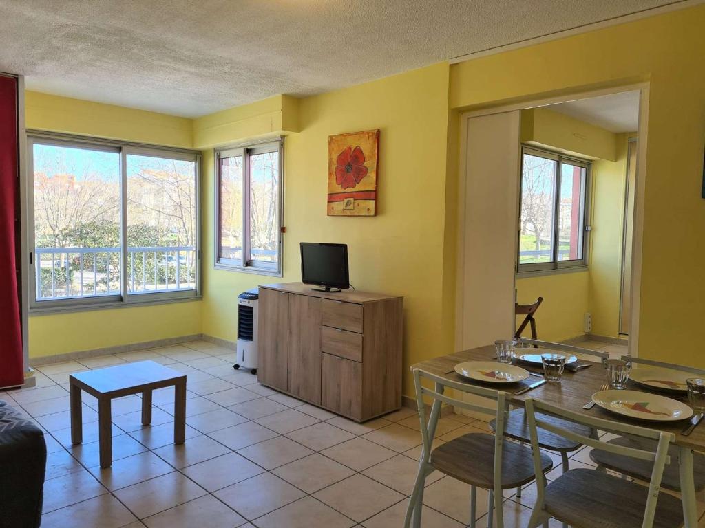 un salon avec une télévision, une table et des chaises dans l'établissement Appartement lumineux 2 pièces, 4 couchages, proche commodités, Cap d'Agde - FR-1-249-378, au Cap d'Agde