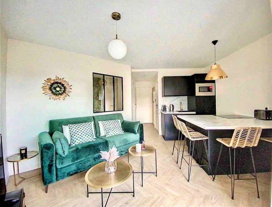 un soggiorno con divano verde e una cucina di Appartement avec balcon Le nid doré - PLACE MORNY a Deauville