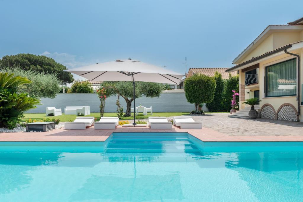 a swimming pool with chairs and an umbrella at Casa dei Sogni - Exclusive Suite in Villa in Lido di Ostia