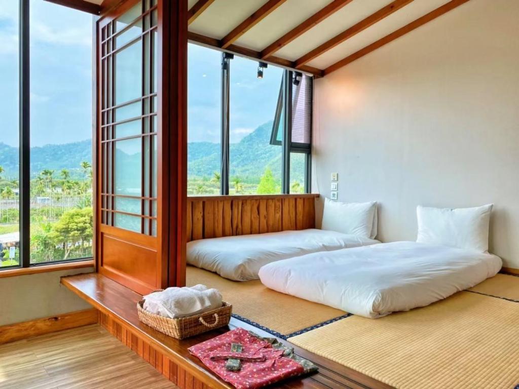 2 Betten in einem Zimmer mit großen Fenstern in der Unterkunft Roaming Cloud Sun Moon Lake B&B in Yuchi