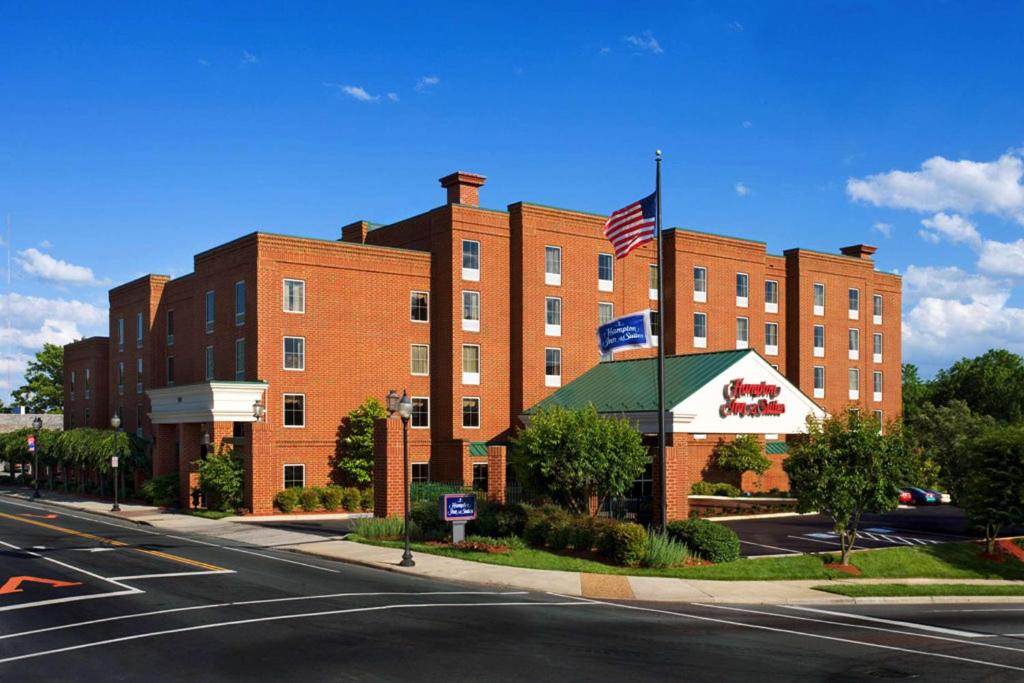 Um grande edifício de tijolos vermelhos com uma bandeira americana. em Hampton Inn & Suites Charlottesville at the University em Charlottesville