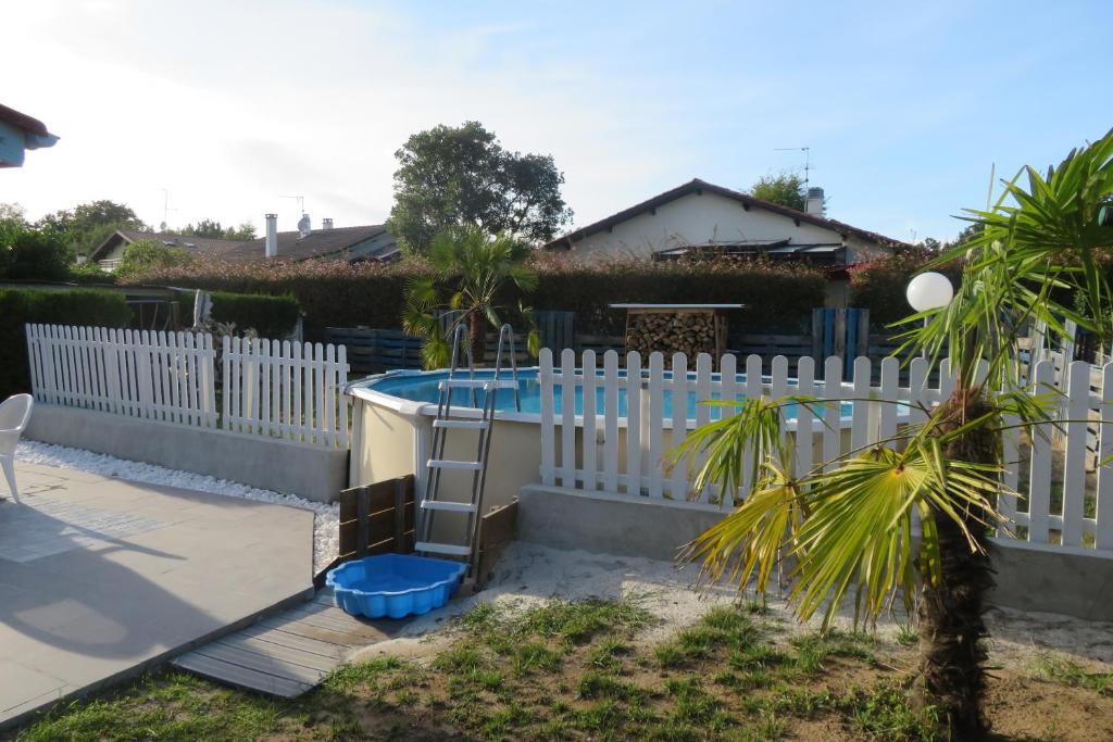 una valla blanca con una piscina en un patio en Maison familiale avec piscine hors sol, en Saint-Vincent-de-Tyrosse