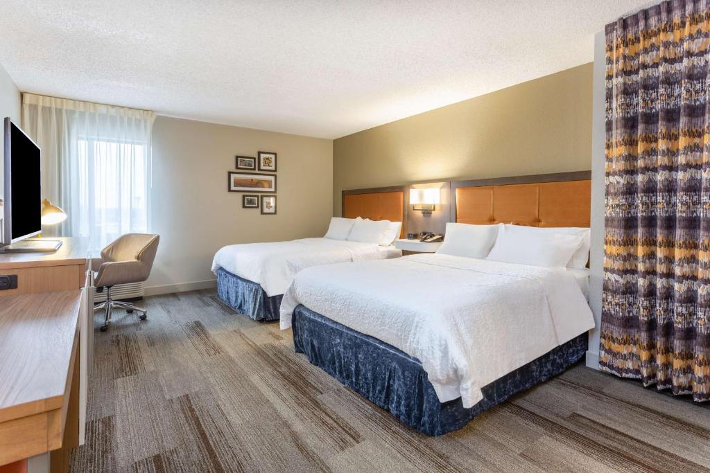 a hotel room with two beds and a flat screen tv at Hampton Inn Cedar Rapids in Cedar Rapids