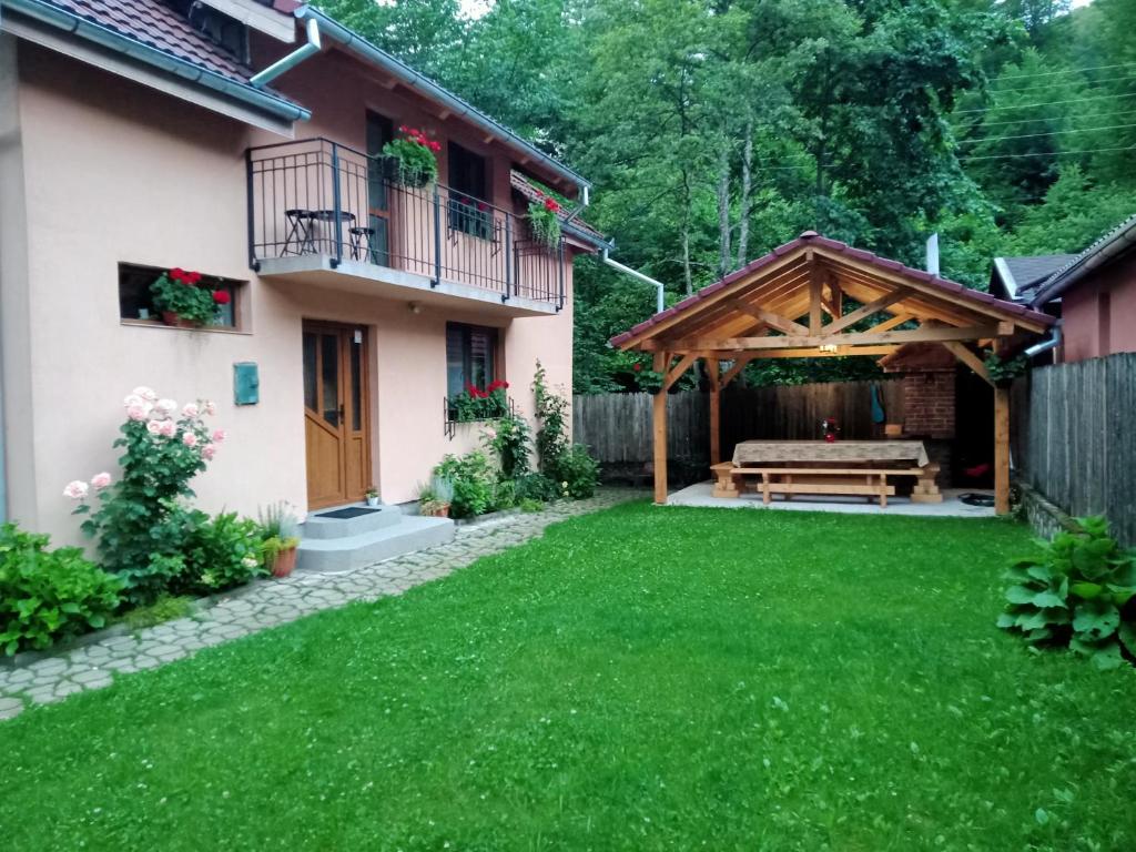 a backyard with a wooden pergola and a bench at Casa Iulia & Matei in Cârțișoara