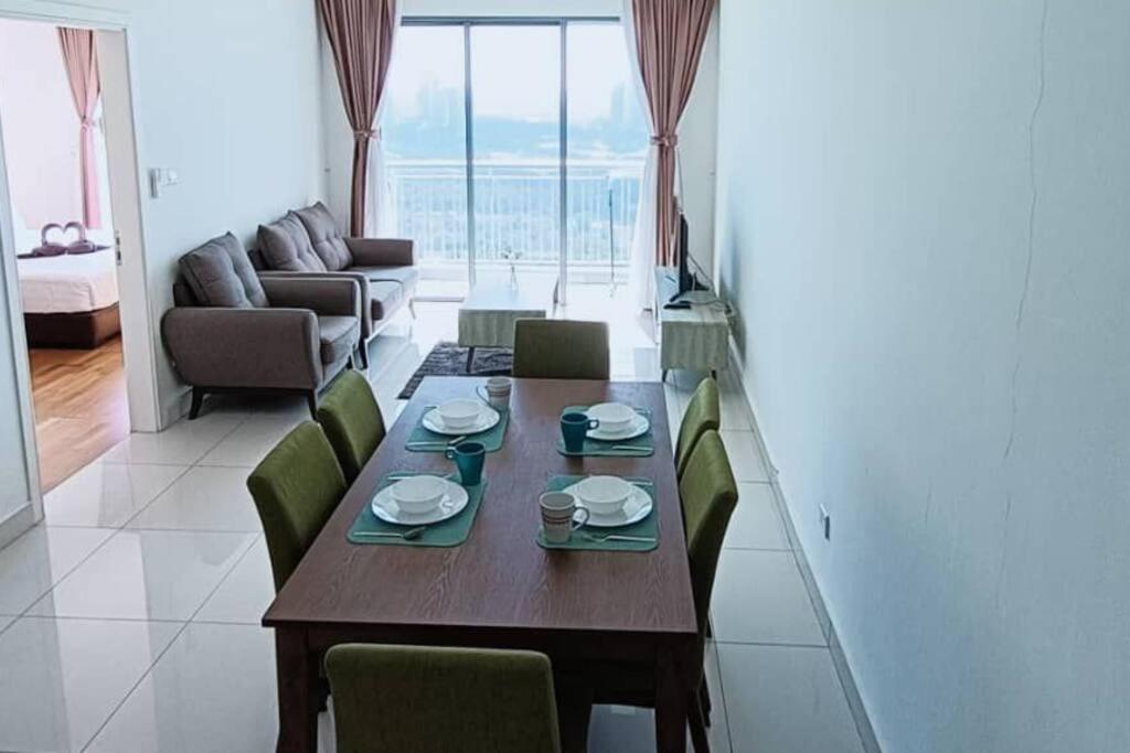 - un salon avec une table en bois et des chaises vertes dans l'établissement Teega Cozy 2 Guests 35th floor WI-FI City View, à Nusajaya