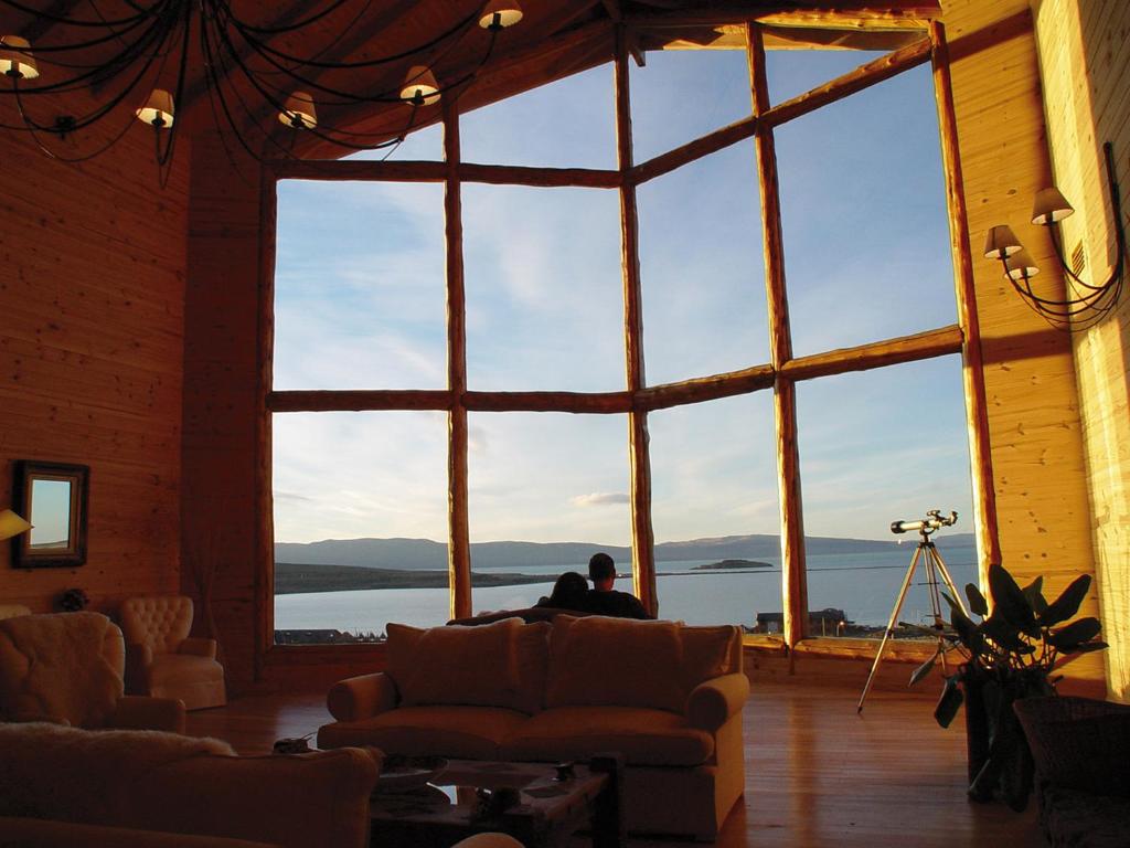 a man sitting on a couch in a room with a large window at Blanca Patagonia Hostería Boutique y Cabañas in El Calafate