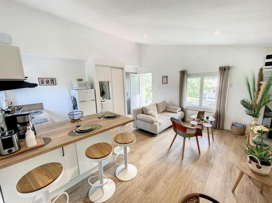 uma sala de estar com um sofá, uma mesa e cadeiras em Les pénates du pastel - Jardin & Terrasse em Villefranche-de-Lauragais