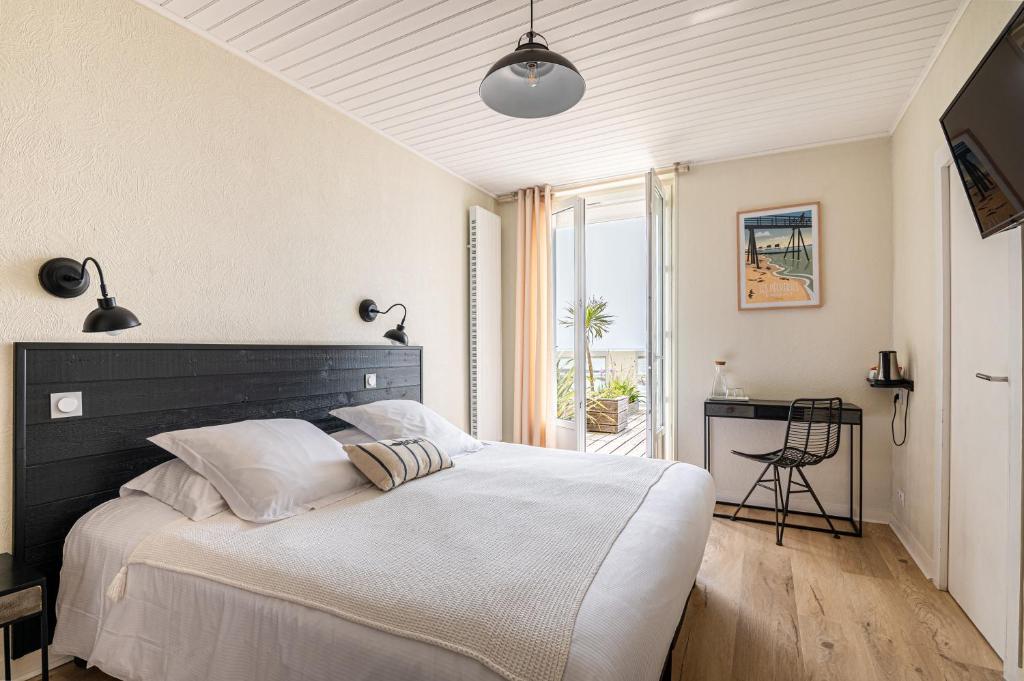 um quarto com uma cama grande e uma cabeceira preta em Hôtel de charme & SPA Le Grand Large em La Bernerie-en-Retz