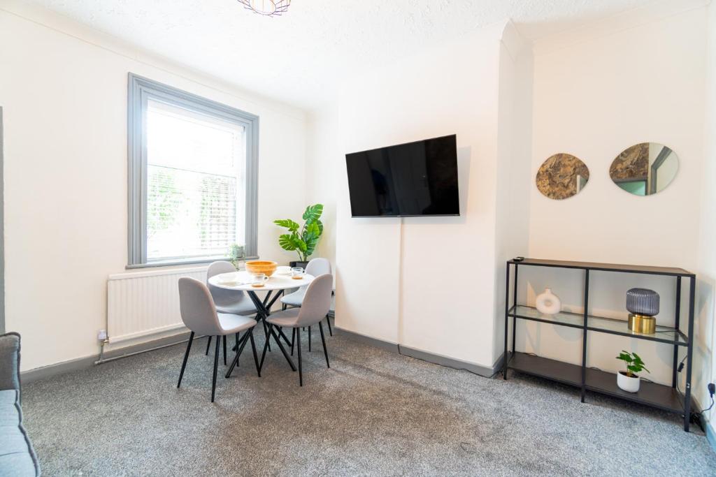 een woonkamer met een tafel en stoelen en een televisie bij Stylish 3 Bedroom House - Central Location in Nottingham