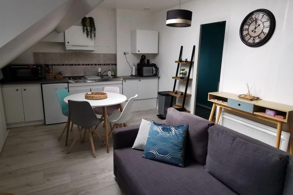 uma sala de estar com um sofá e uma mesa com um relógio em Appartement cosy, 300m de la mer em Donville-les-Bains