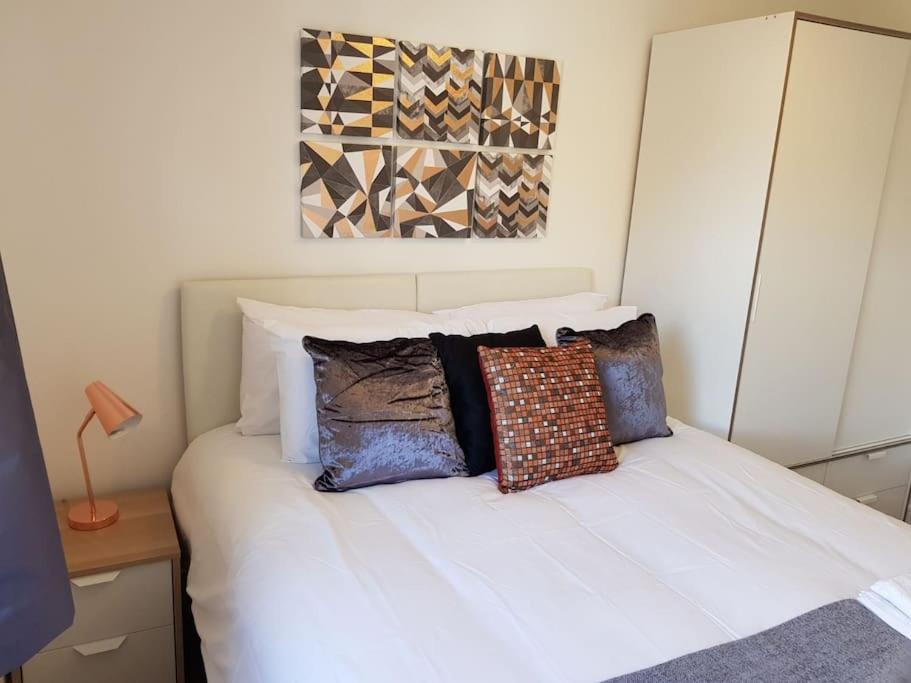 een slaapkamer met een wit bed met kussens erop bij Guest Homes - Propelair Apartment in Colchester