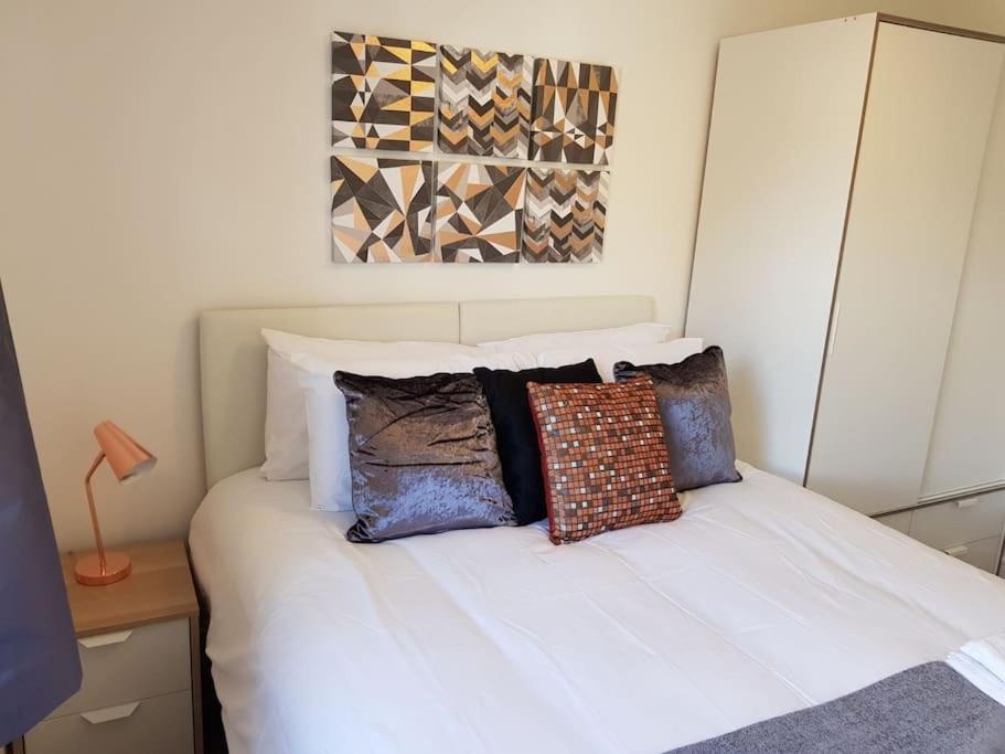 Guest Homes - Propelair Apartment في كولشستر: غرفة نوم بسرير ابيض عليها مخدات