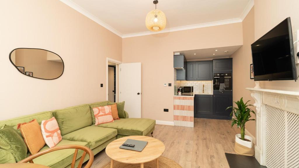- un salon avec un canapé vert et une cheminée dans l'établissement Lamington Apartments - Hammersmith, à Londres