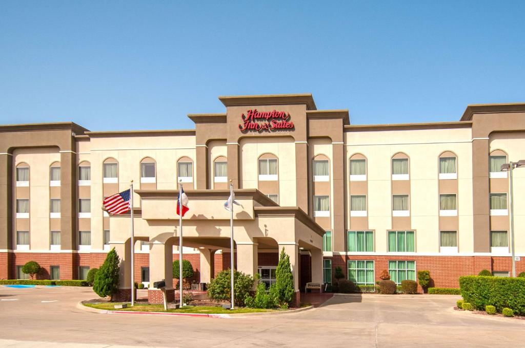 una vista exterior de un hotel con dos banderas americanas en Hampton Inn and Suites Waxahachie, en Waxahachie