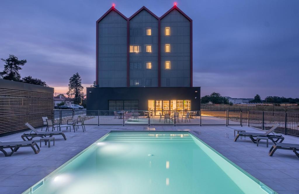 a pool with chairs and a building in the background at The Originals City, Relais d'Estillac, Agen Sud in Estillac