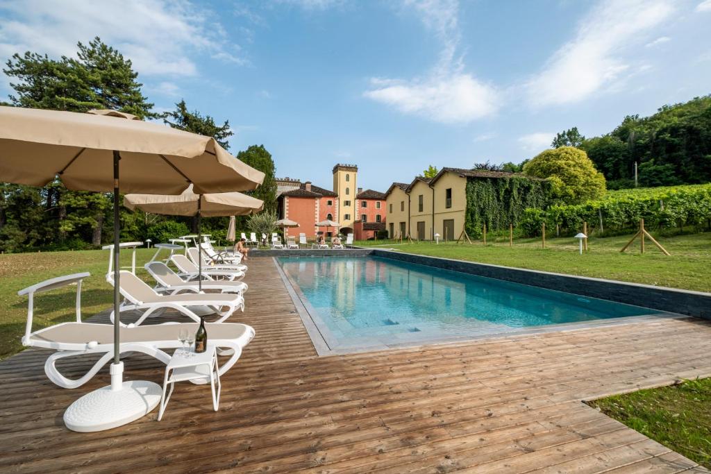 a pool with chairs and umbrellas next to a house at Villa Clementina - Prosecco Country Hotel in San Pietro di Feletto