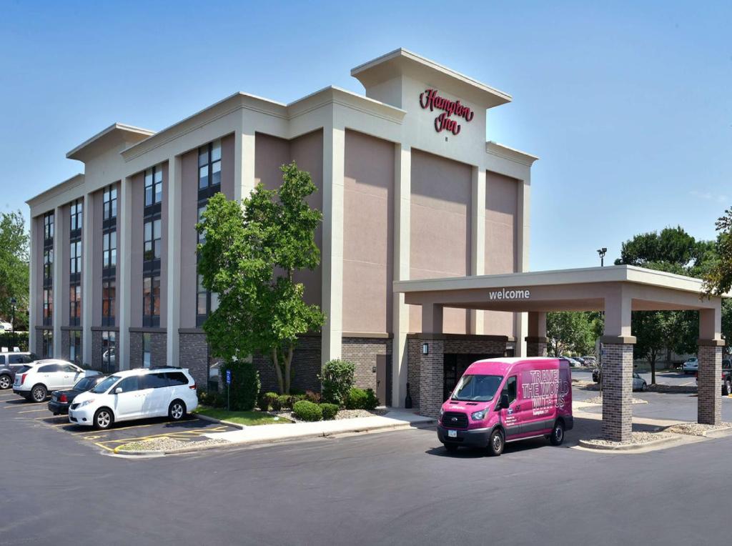 um hotel com uma carrinha rosa estacionada num parque de estacionamento em Hampton Inn Des Moines-Airport em Des Moines