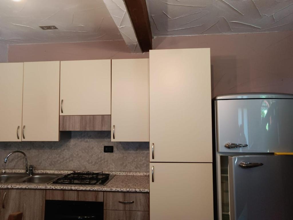 uma cozinha com armários brancos e um frigorífico de aço inoxidável em OASI DEL GARDA 6 em Monzambano
