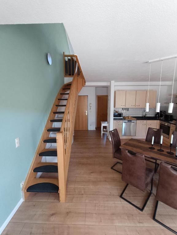 a living room with a wooden staircase and a dining table at FeWo Vineta in Barth