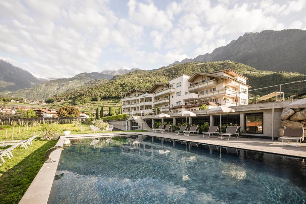 un hotel con una piscina con montañas de fondo en Residence Hirzer, en Lagundo