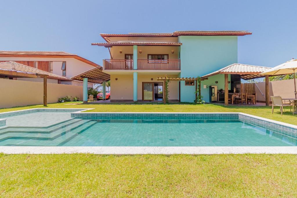 a villa with a swimming pool in front of a house at PF55 Ótima Casa 4 Suítes - Praia do Forte in Farol