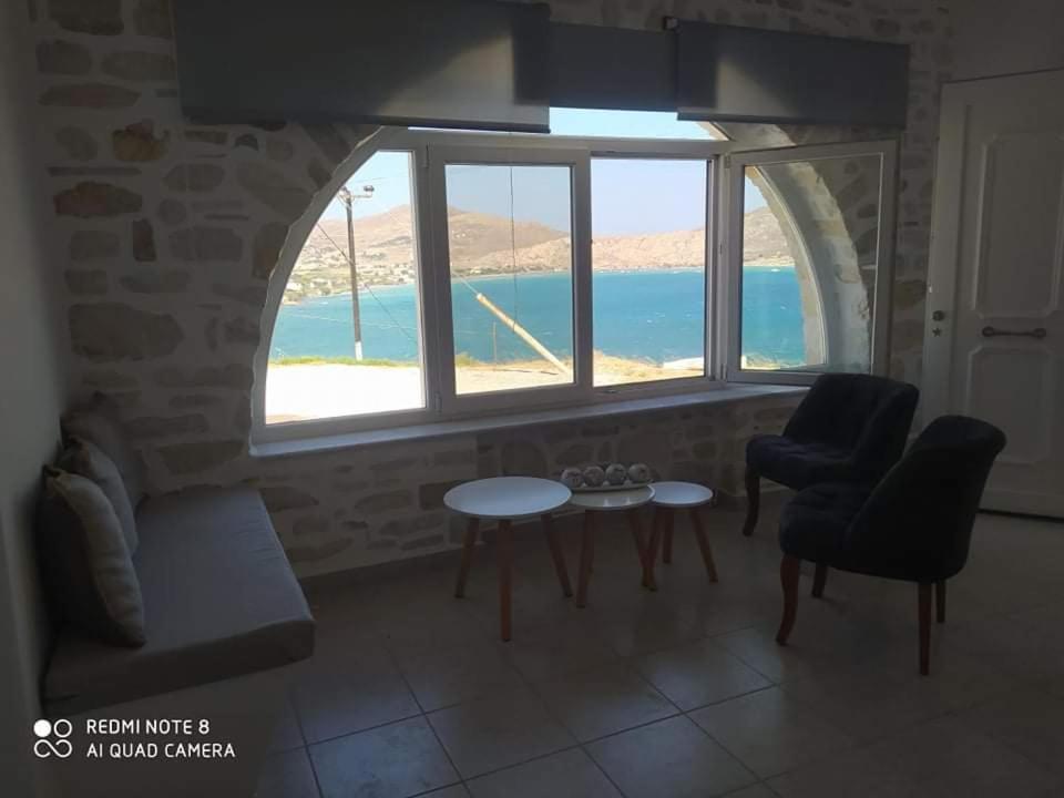 a living room with a large window and a table and chairs at Sea View Stone House in Naousa
