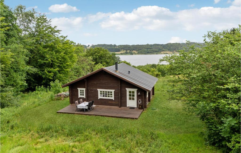 a small cabin in a field with a deck at Amazing Home In Mariager With House Sea View in Mariager