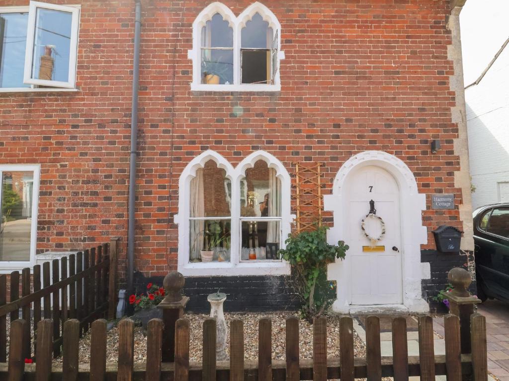 a brick house with a white door and a fence at Harmony Cottage in Bungay