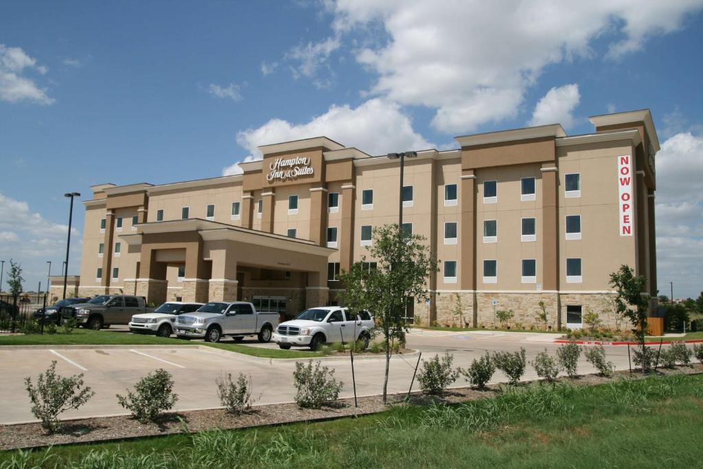 a hotel with cars parked in front of it at Hampton Inn & Suites Cleburne in Cleburne