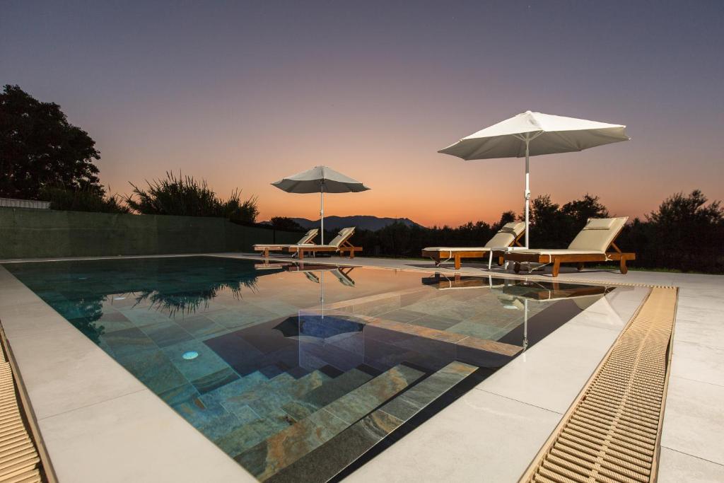 a swimming pool with two chairs and an umbrella at Nikis Apartments Kisamos in Drapaniás